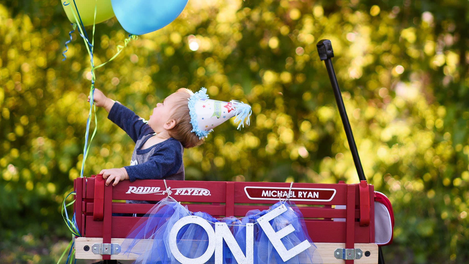 One year old in a wagon reaching for a balloon during a family photography session in Greenville,SC.