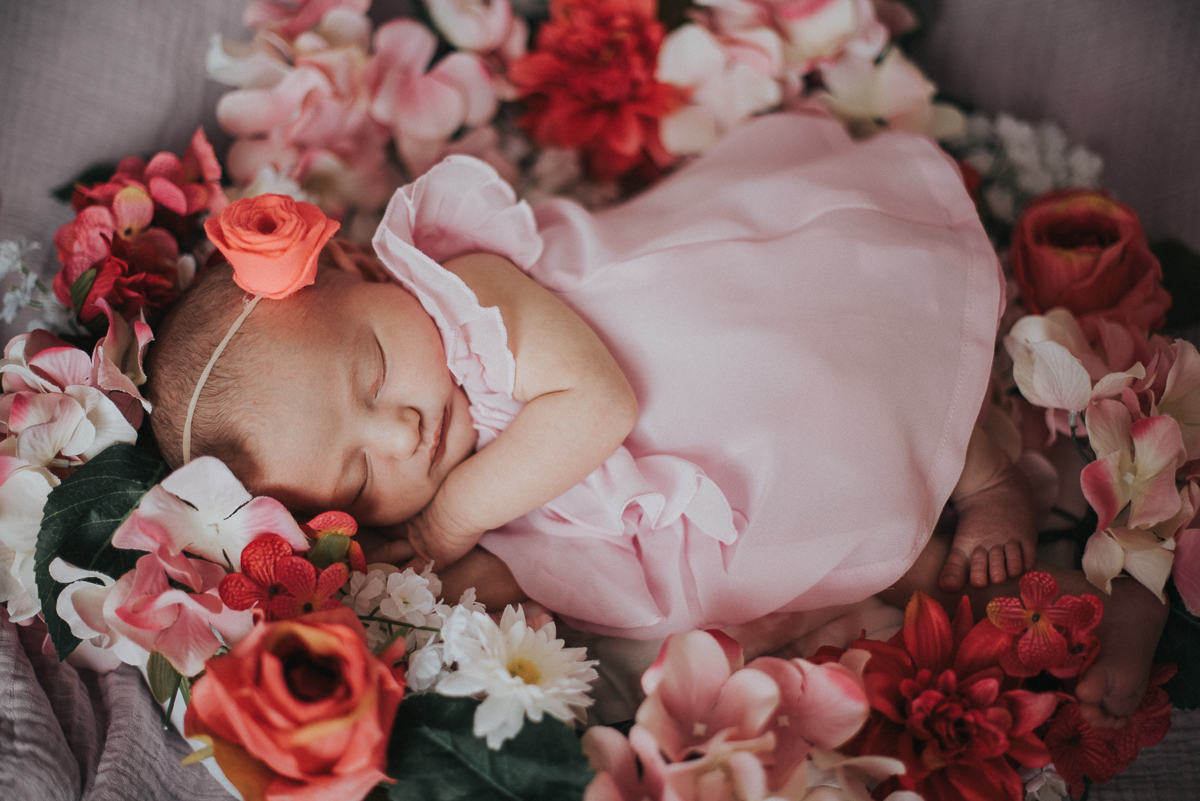 7 day old baby girl laying in flowers wearing a pink dress by Greenville SC Newborn Photographer Elizabeth and Charles.