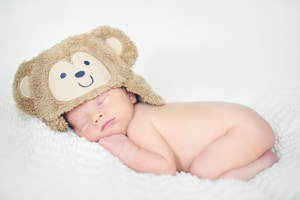 Newborn baby boy wearing a teddy bear hat.