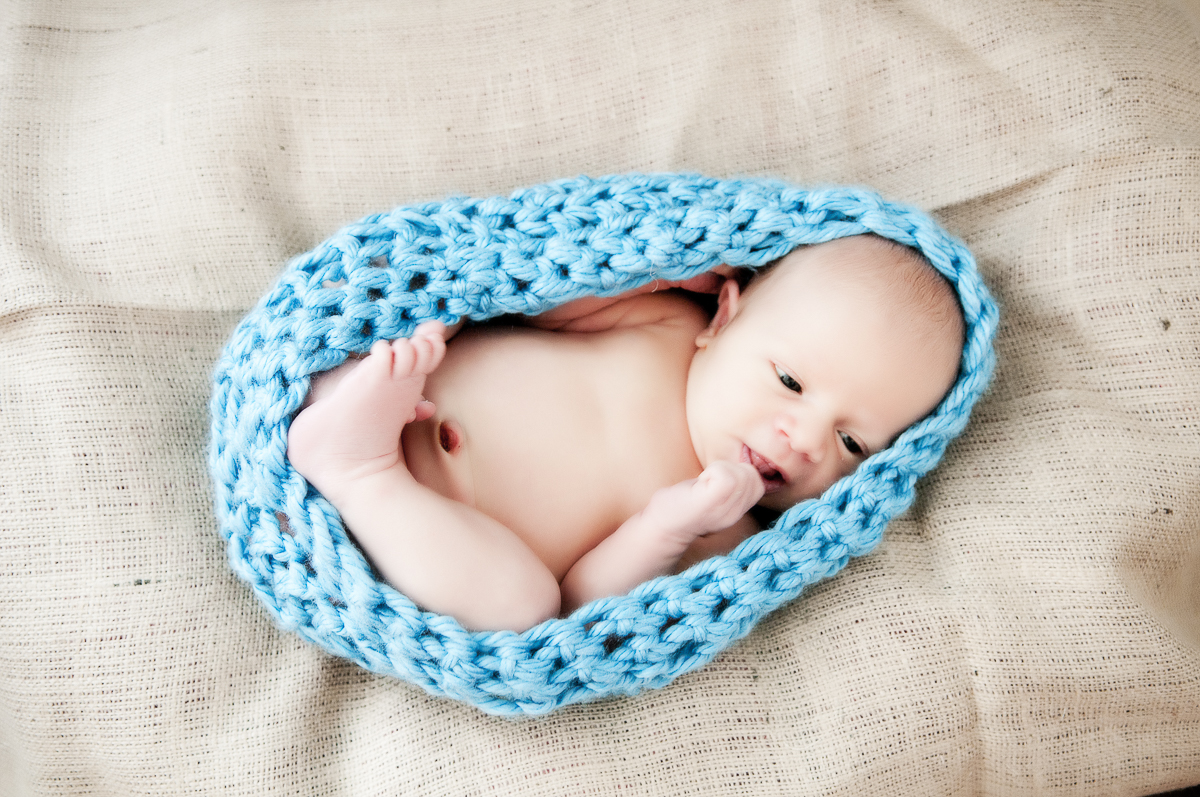 Baby boy in a blue knitted cocoon.