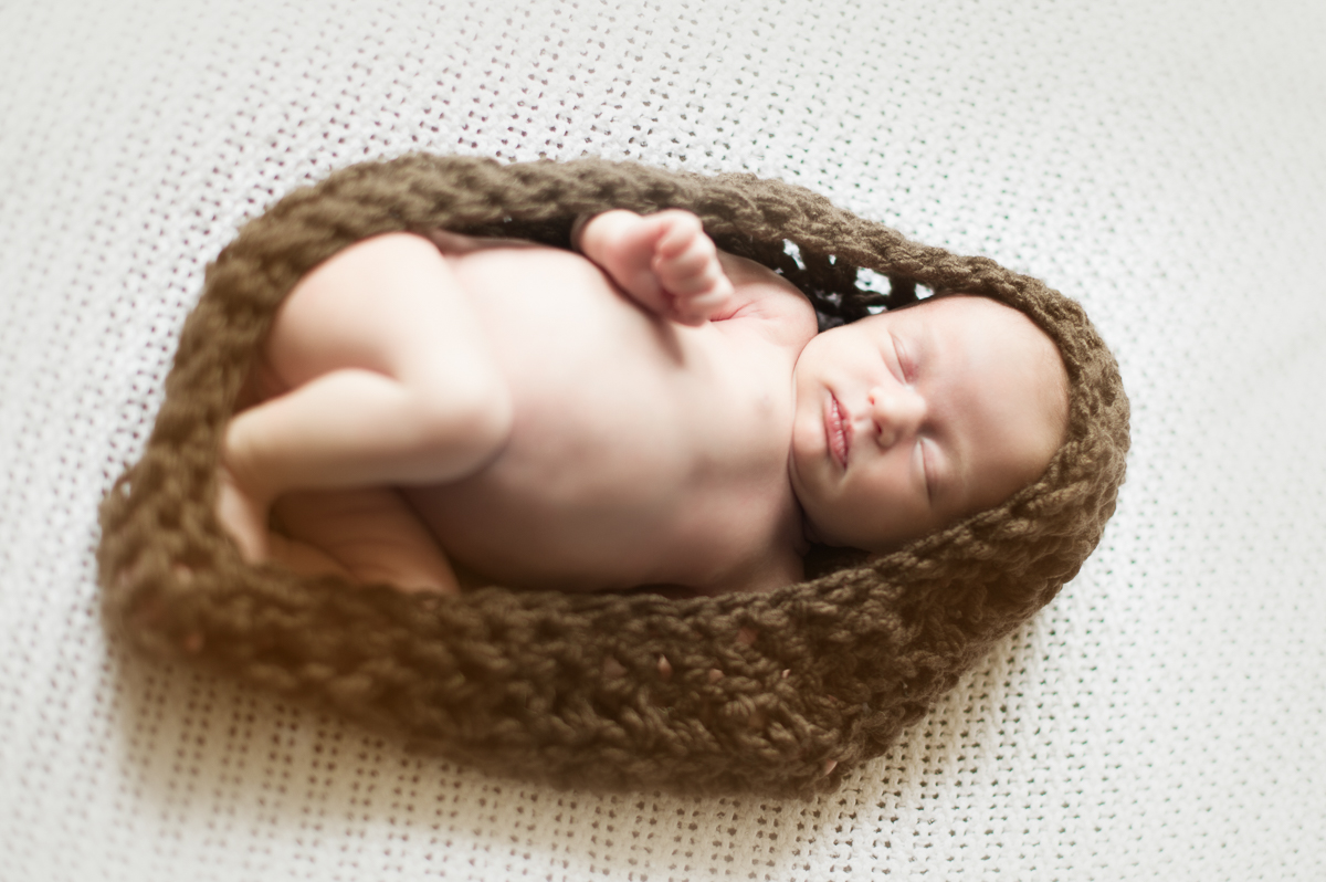 Baby in a knitted cocoon during a newborn photography session.